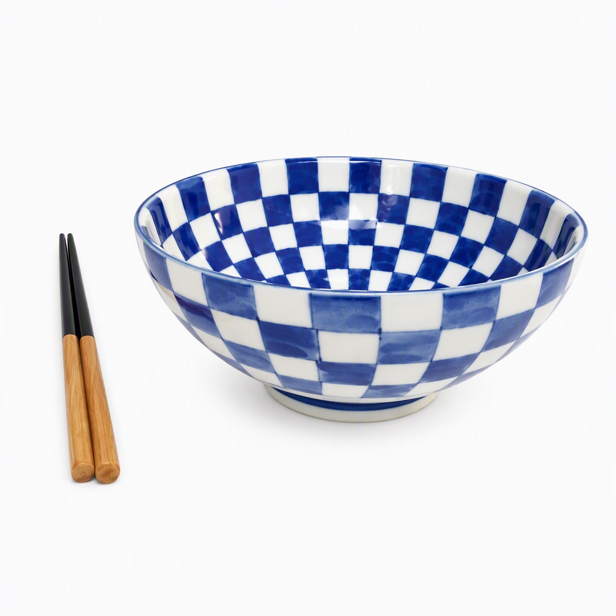 Grand bol japonais à damier en céramique présenté de côté avec une paire de baguettes japonaises